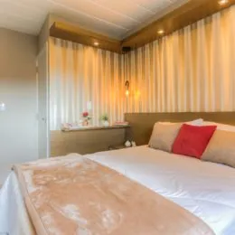 Quarto com cama grande e cortinas claras.