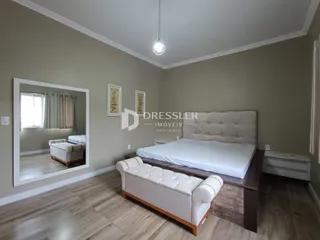 Quarto com cama e espelho em ambiente claro.