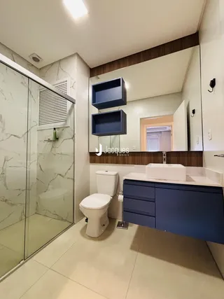 Banheiro moderno com box de vidro e revestimento de mármore.