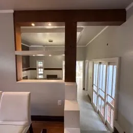 Hall de entrada com viga de madeira visível na passagem.