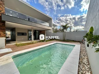 A foto mostra a fachada de uma casa moderna com uma piscina externa.