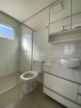 Banheiro moderno com revestimento branco e piso claro.
