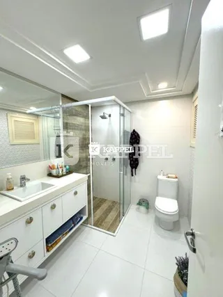 Foto de um banheiro com bancada, vaso sanitário e box de vidro.