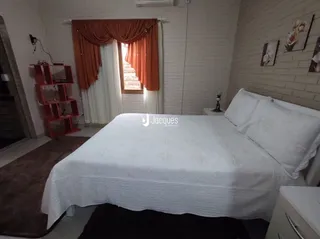 Quarto com cama de casal e cortinas cor de terracota.