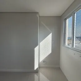 Ambiente interno com paredes brancas e iluminação natural forte.