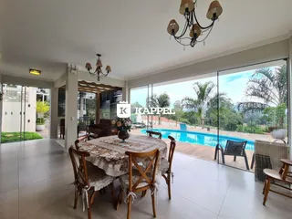 Uma sala de jantar com mesa de madeira e acesso a uma área externa com piscina.