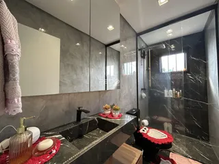 Banheiro com revestimento em mármore escuro e box de vidro.