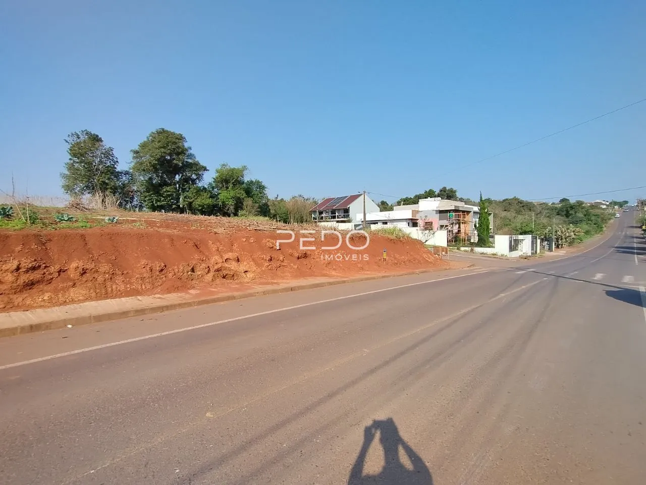 Vista exterior da propriedade mostrando uma estrada e um talude de terra no fundo.