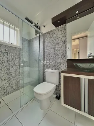 Banheiro com box de vidro e revestimento cerâmico na residência.