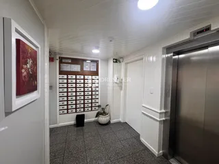 Hall de entrada de uma residência com parede branca e piso cinza.