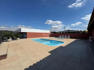 Vista externa de uma área de piscina e pátio em uma propriedade no Brasil.