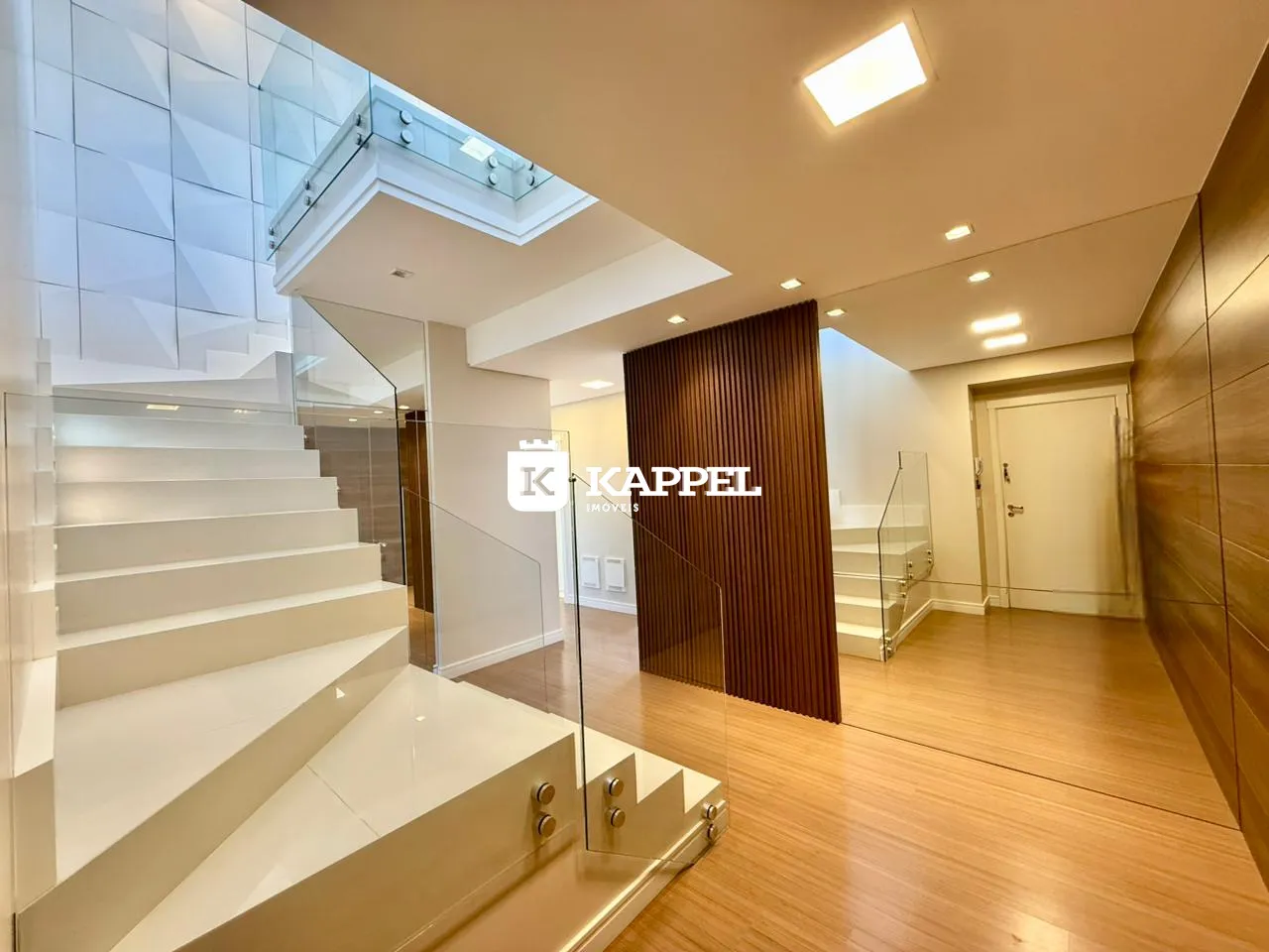 Hall de entrada com piso de madeira e guarda-corpo de vidro.