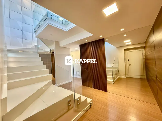 Hall de entrada com piso de madeira e guarda-corpo de vidro.