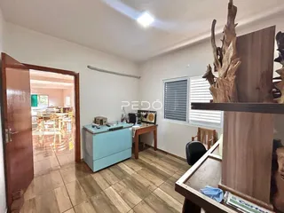 Interior de uma sala de estar com piso de madeira e porta de entrada para outra área.