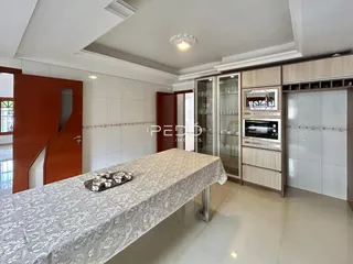 Ambiente interno com mesa de jantar e armários na cozinha.