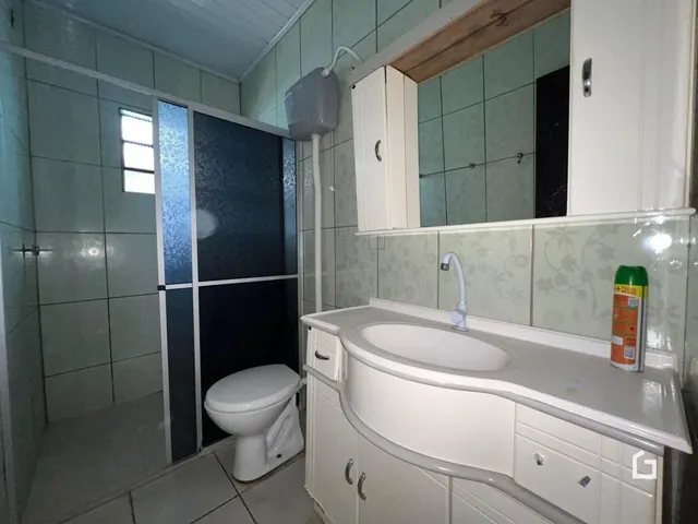 Banheiro com revestimento cerâmico e louças brancas.