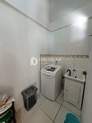 Vista de um corredor interno com um tanque e máquina de lavar roupa.