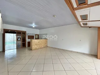 Sala de estar ampla com piso de cerâmica e parede de destaque na residência.
