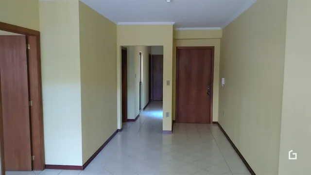 Corredor interno de uma residência com paredes amarelas e piso de cerâmica.