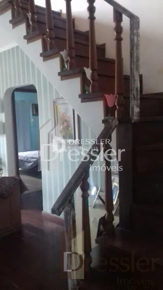Vista de um corredor com degraus de madeira em uma residência.