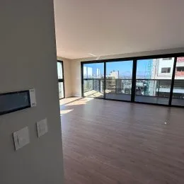 Sala de estar com piso de madeira e grandes janelas que dão vista para o exterior.