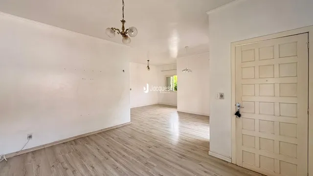 Ambiente interno de uma sala de estar com piso de madeira clara.