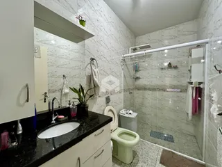 Foto de um banheiro com revestimento de azulejos brancos e box de vidro.