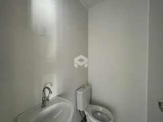 Banheiro com azulejos brancos e louças sanitárias.