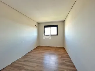 Vista interna de um cômodo com piso de madeira e paredes brancas.