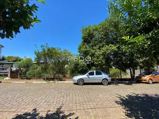 Vista externa de uma propriedade em Lajeado, Brasil, com árvores e veículos estacionados.