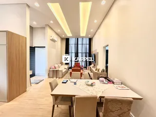 Sala de estar moderna com sofá e mesa de jantar em ambiente claro.