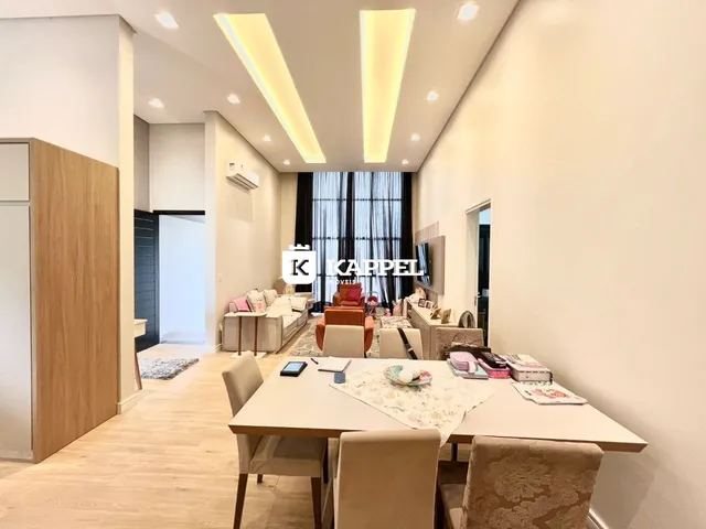 Sala de estar moderna com sofá e mesa de jantar em ambiente claro.
