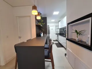 Imagem de uma sala de estar interna com paredes brancas e detalhes em madeira.