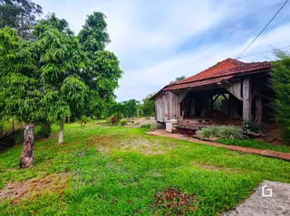 Vista externa de um terreno gramado com uma estrutura de madeira ao fundo.