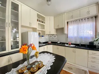 Foto de uma cozinha com armários brancos e bancadas escuras.