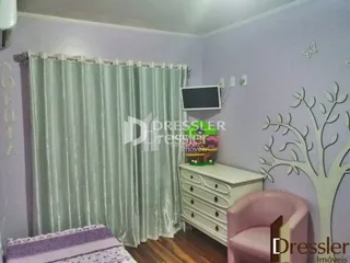 Quarto com cortinas e cômoda de madeira.