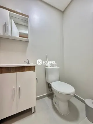 Foto interna de um banheiro com vaso sanitário e armário de bancada.