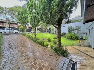 Vista da entrada de uma propriedade com calçada de pedras e vegetação densa.