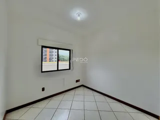 Ambiente interno de uma sala com piso de cerâmica e paredes brancas.