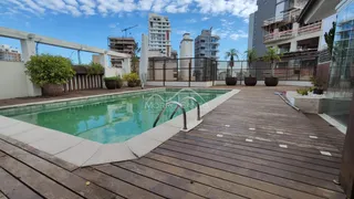 Piscina externa com deck de madeira em uma residência.