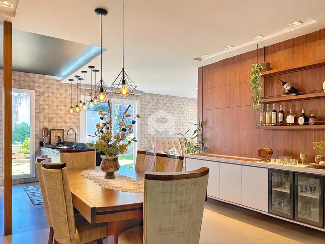 Sala de jantar com mesa de madeira e cozinha moderna em um apartamento.
