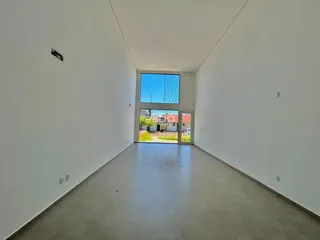 Corredor longo com paredes brancas e piso claro de uma residência.