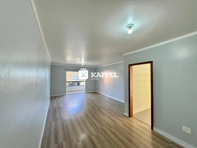 Vista interna de uma sala com piso de madeira clara e paredes em tom de azul claro.