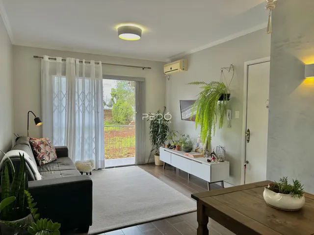 Sala de estar iluminada com vista para o exterior e cortinas brancas.