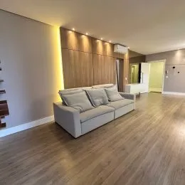 Sala de estar com painel de madeira e piso de madeira clara.