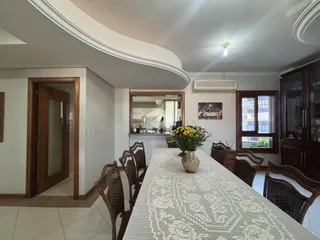 Vista de uma sala de jantar com mesa de vime e portas de madeira em uma residência.