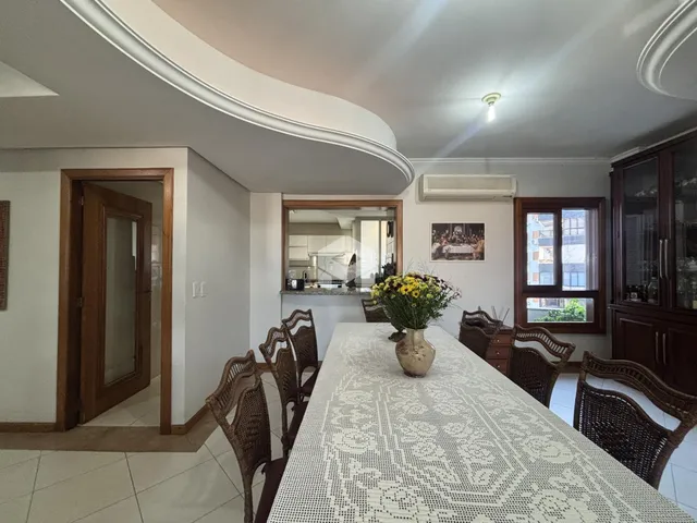 Vista de uma sala de jantar com mesa de vime e portas de madeira em uma residência.
