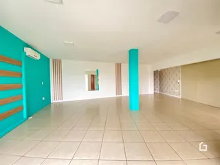 Ambiente interno de uma sala ampla com piso de cerâmica clara e paredes coloridas.