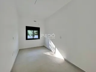Ambiente interno de uma sala com paredes brancas e piso claro.