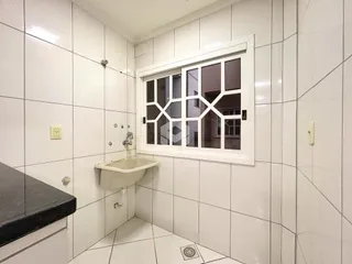 Foto de um banheiro com revestimento cerâmico branco e janela.